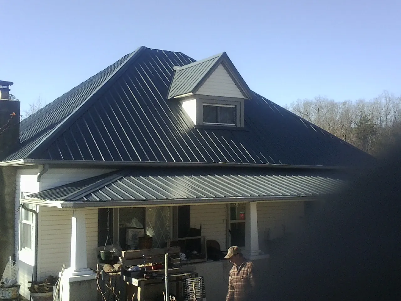 Dark blue standing seam metal roof with a dormer above a front porch in Kohler