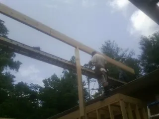 Carpenter setting a ridge beam over a new addition frame — Ice Dam Removal by Roofing Brothers in Kohler