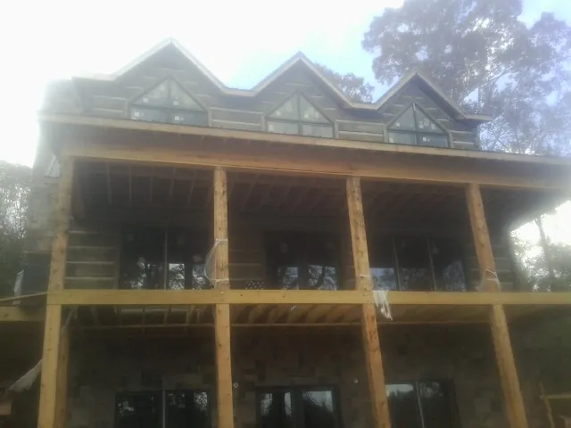 Dormers and porch framing on a large log home under construction — Roof Coating work by our crew in Kohler