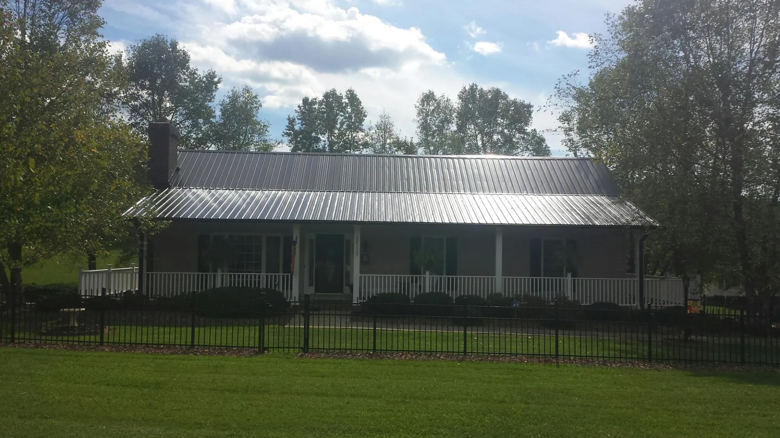 Gray metal roof on a brick ranch with a full width front porch — Gutter Guard Installation work by our crew in Kohler