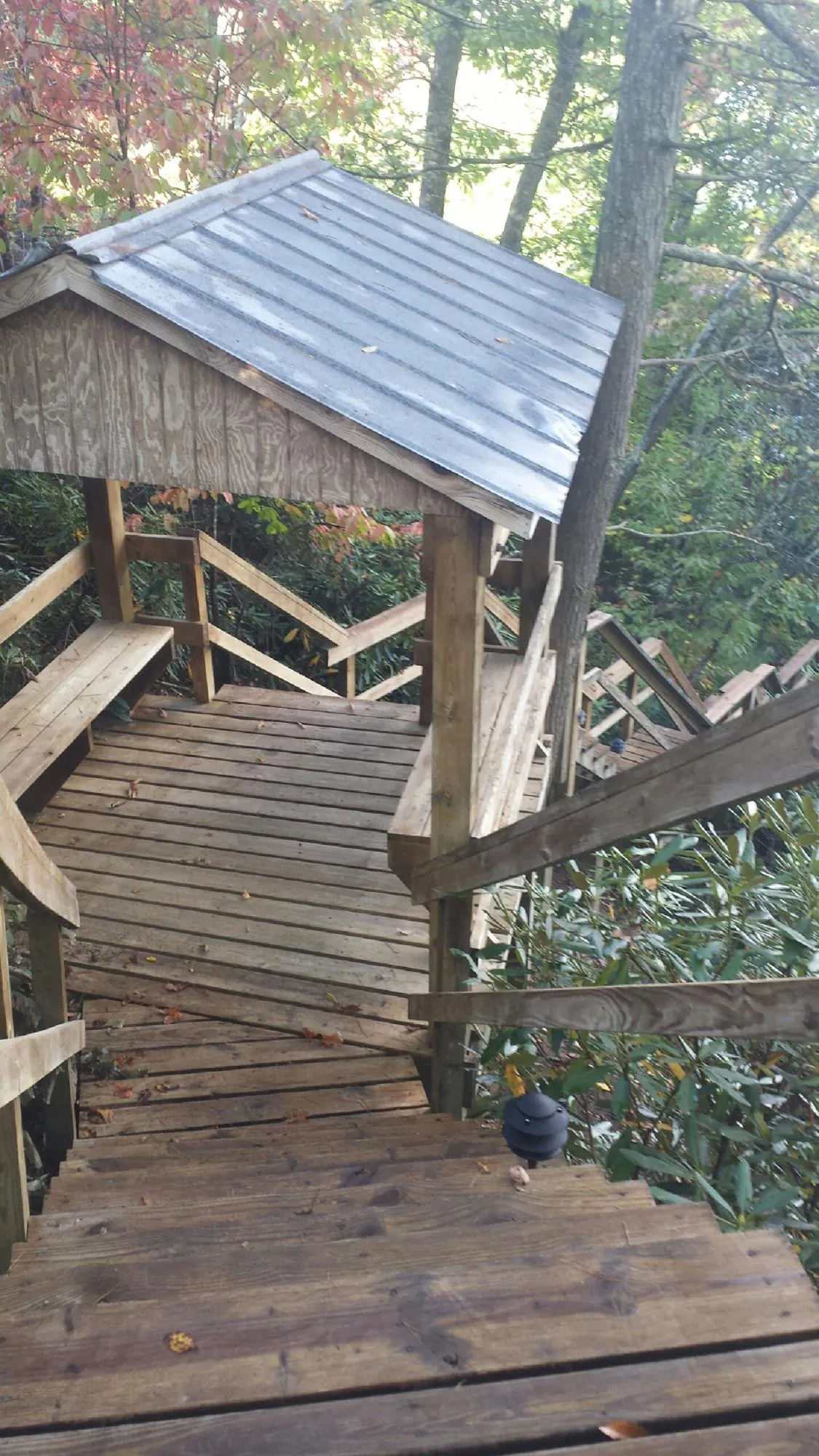 Metal roofed shelter over wooden steps on a wooded walkway — Skylight Repair & Installation work by our crew in Kohler