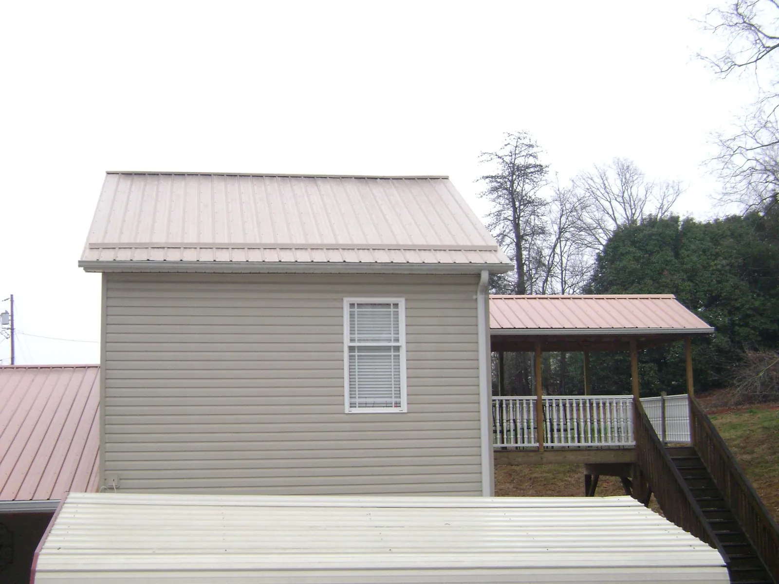 Tan metal roofs on a two story addition and attached porch, from a Roof Replacement job in Kohler