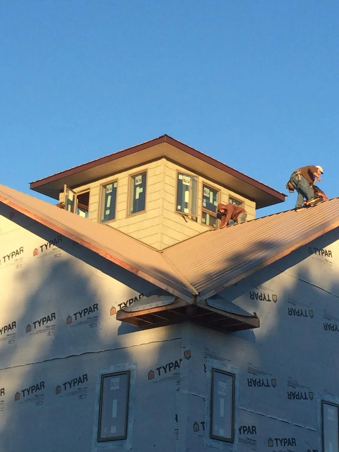 Roofers working around a rooftop cupola on a new metal roof at sunset — Roof Waterproofing in Kohler by Roofing Brothers